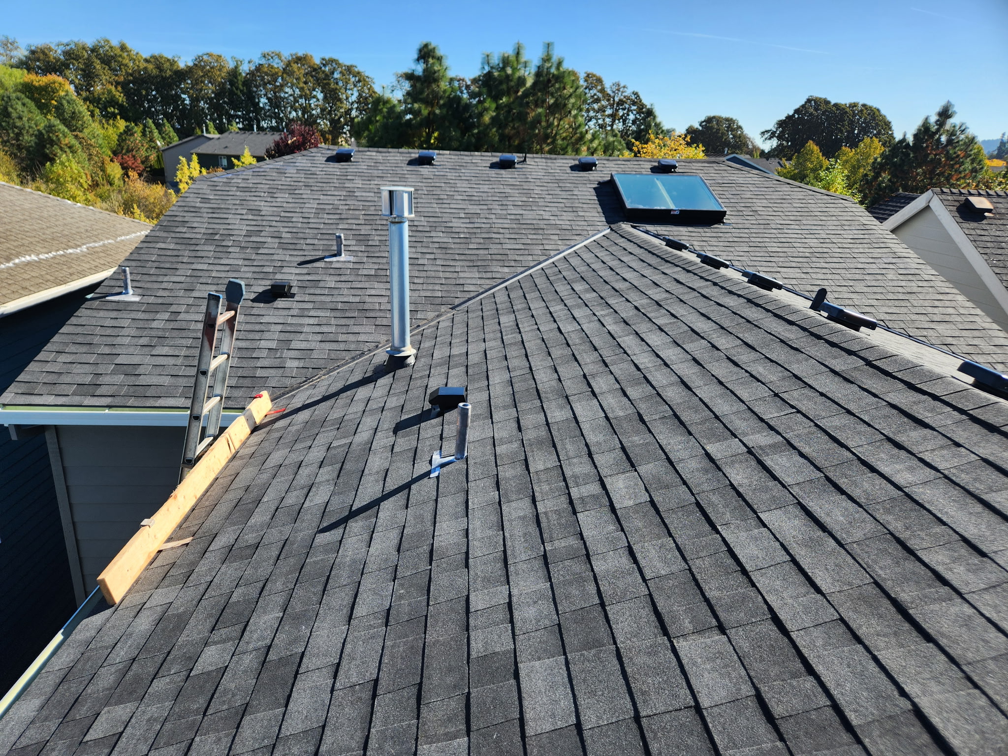 Freshly completed composition shingle roof with a new skylight