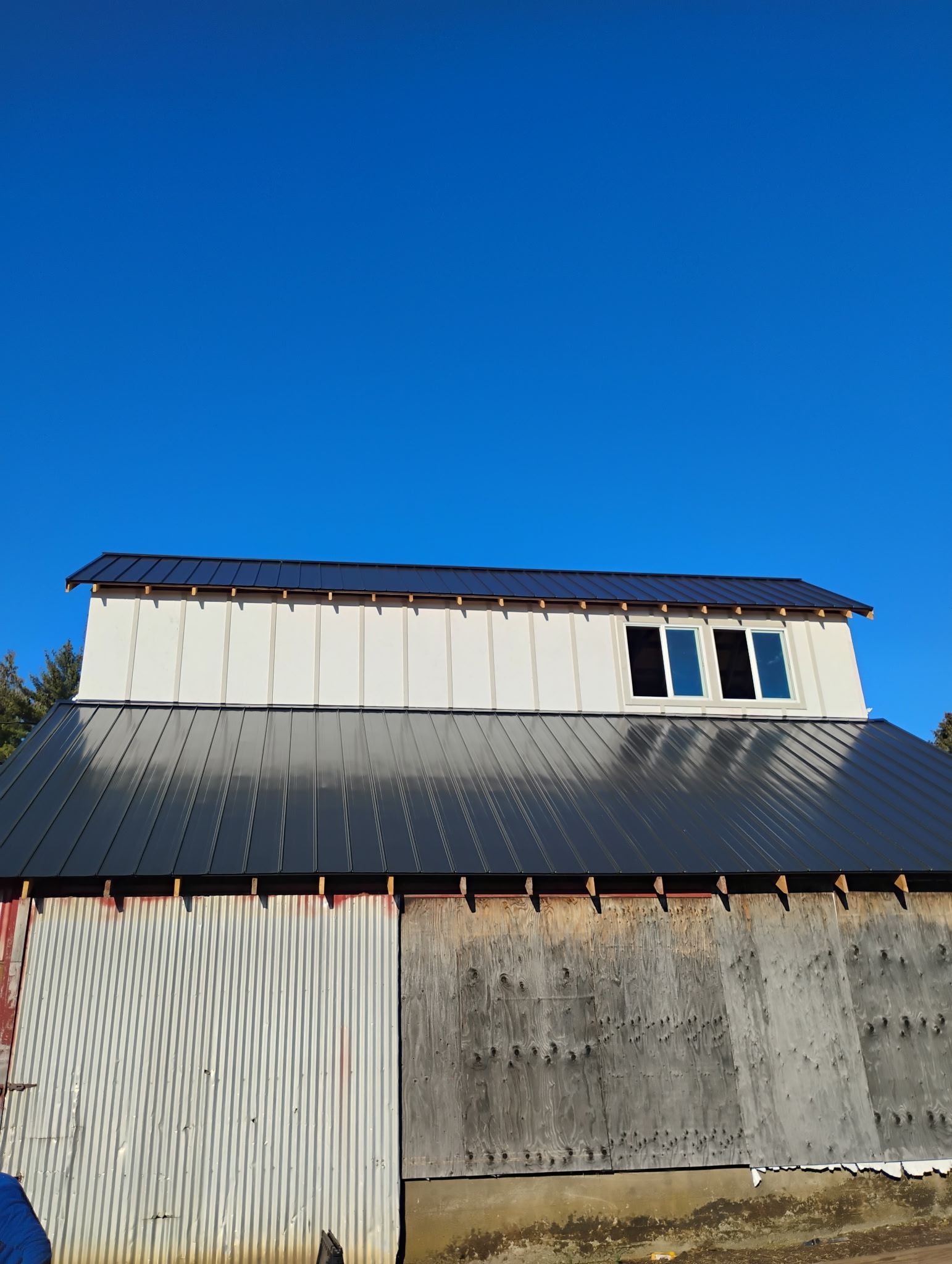 Standing-seam metal roof installation on a shop building, mid-project